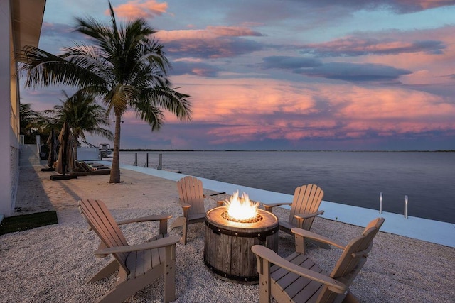 patio terrace at dusk with a water view and a fire pit