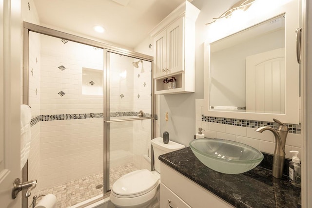 bathroom with vanity, backsplash, a shower with door, and toilet