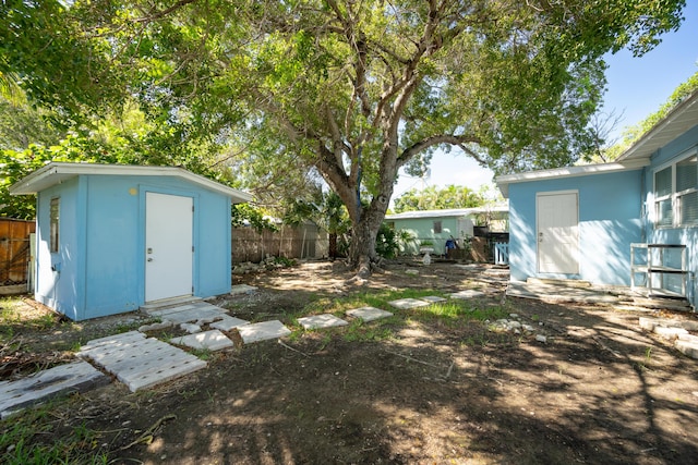 view of yard with a fenced backyard, a storage unit, and an outbuilding