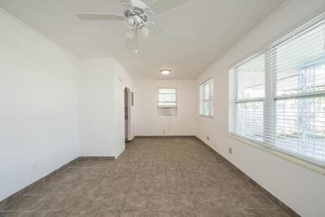 spare room featuring crown molding, baseboards, arched walkways, cooling unit, and a ceiling fan