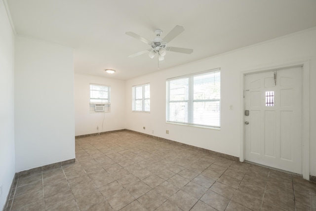 interior space with baseboards, a ceiling fan, and ornamental molding