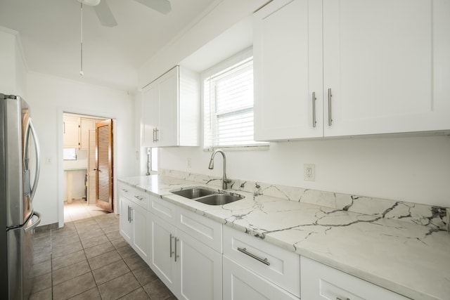 kitchen with a ceiling fan, light stone countertops, a sink, white cabinets, and freestanding refrigerator