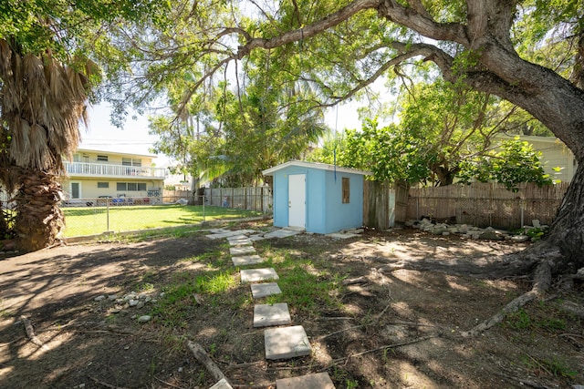view of yard with an outdoor structure, a fenced backyard, and a shed