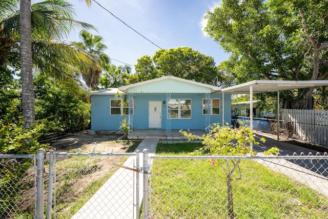 view of front of home featuring a fenced front yard, aphalt driveway, an attached carport, a gate, and covered porch