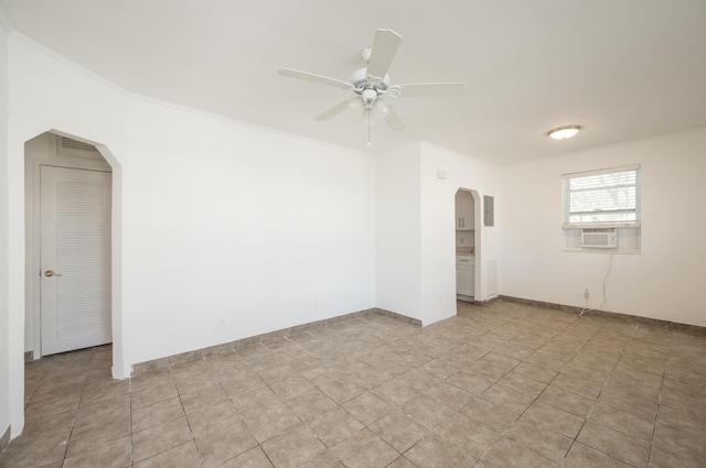 empty room featuring ceiling fan, crown molding, arched walkways, baseboards, and cooling unit