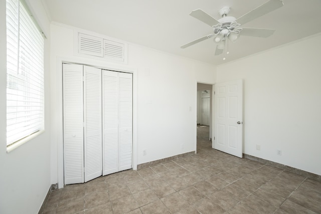 unfurnished bedroom featuring crown molding, baseboards, ceiling fan, and a closet