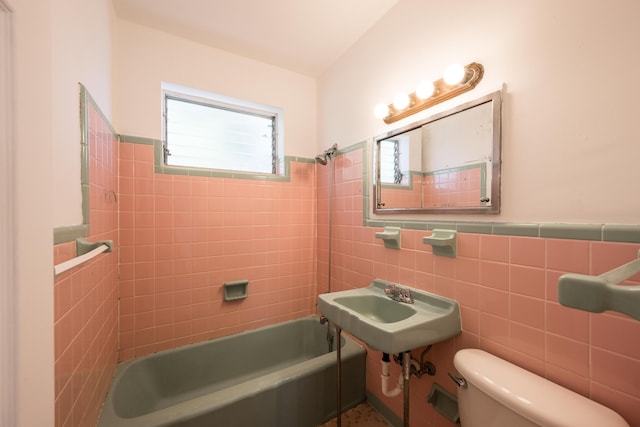 bathroom featuring  shower combination, wainscoting, toilet, tile walls, and a sink
