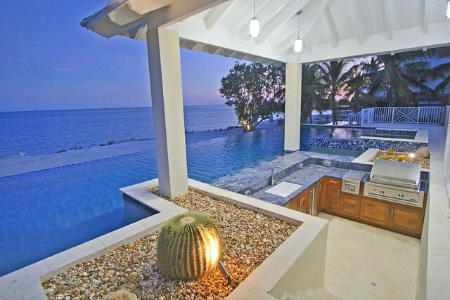 30 Ocean Front Dr, Key Largo, FL 33037 - patio terrace at dusk featuring a water view, area for grilling, an in ground hot tub, exterior kitchen, and a fire pit