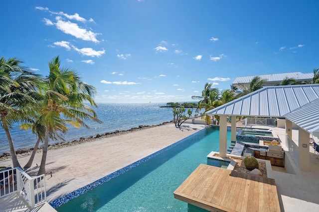 view of pool with a view of the beach, an outdoor kitchen, a patio, and a water view