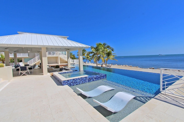 view of swimming pool with a gazebo, a patio area, an in ground hot tub, and a water view