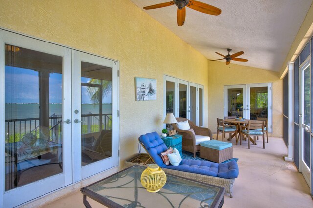 sunroom / solarium featuring french doors, a water view, ceiling fan, and vaulted ceiling