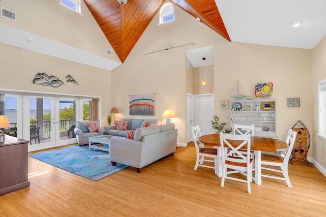 living room with light hardwood / wood-style flooring, high vaulted ceiling, and french doors