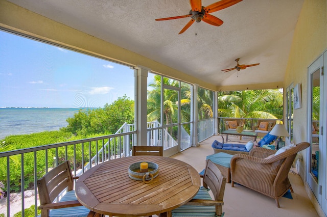 sunroom featuring vaulted ceiling, ceiling fan, and a water view