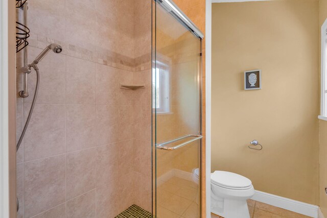 bathroom featuring walk in shower, tile patterned floors, and toilet