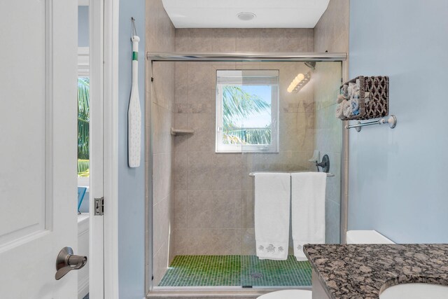 bathroom featuring vanity, a shower with shower door, and toilet