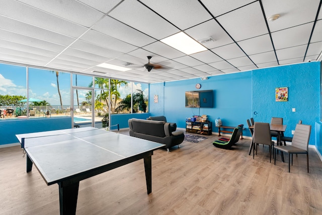 playroom featuring ceiling fan, a drop ceiling, and light wood-type flooring