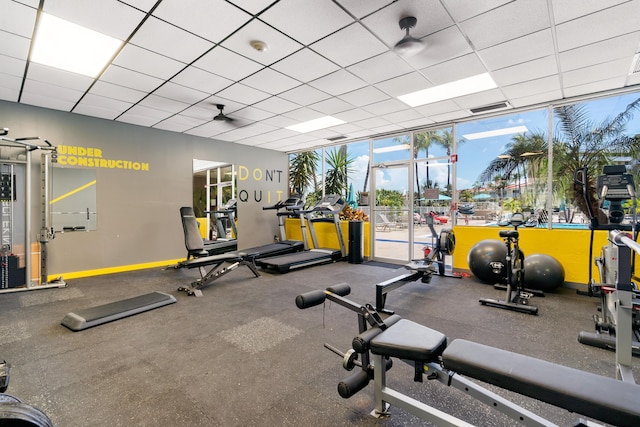 gym with floor to ceiling windows and a drop ceiling