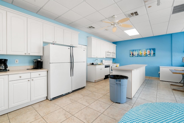 kitchen featuring a kitchen island, white cabinetry, ceiling fan, a drop ceiling, and white appliances