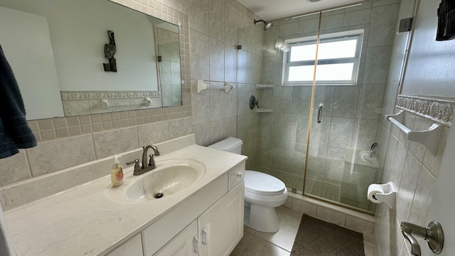 bathroom featuring tile walls, vanity, a shower with door, and toilet