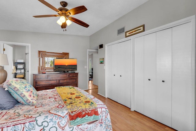 bedroom featuring multiple closets, ceiling fan, and light hardwood / wood-style flooring