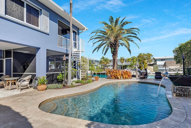 view of pool featuring pool water feature, a sunroom, and a patio