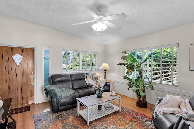 living room featuring hardwood / wood-style flooring, ceiling fan, lofted ceiling, and a textured ceiling