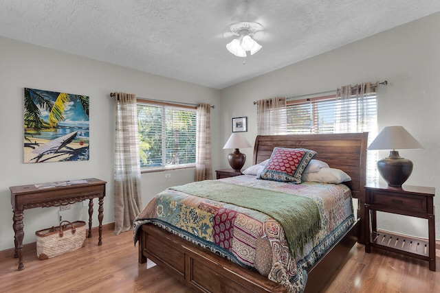 bedroom with wood-type flooring, vaulted ceiling, and a textured ceiling