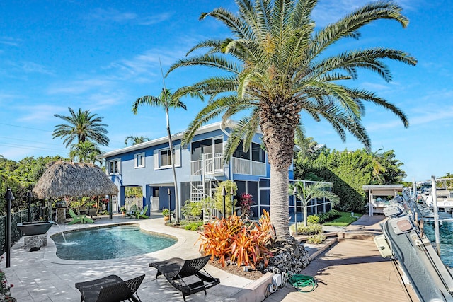 view of swimming pool with a gazebo, pool water feature, a sunroom, and a patio