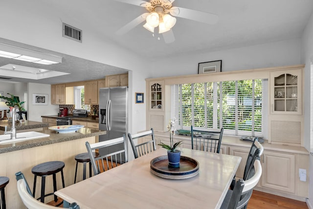 dining room featuring ceiling fan, sink, and light hardwood / wood-style floors