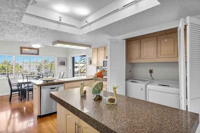 kitchen featuring a textured ceiling, light wood-type flooring, dishwasher, a kitchen island, and washing machine and dryer