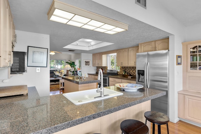 kitchen featuring sink, kitchen peninsula, appliances with stainless steel finishes, and a breakfast bar