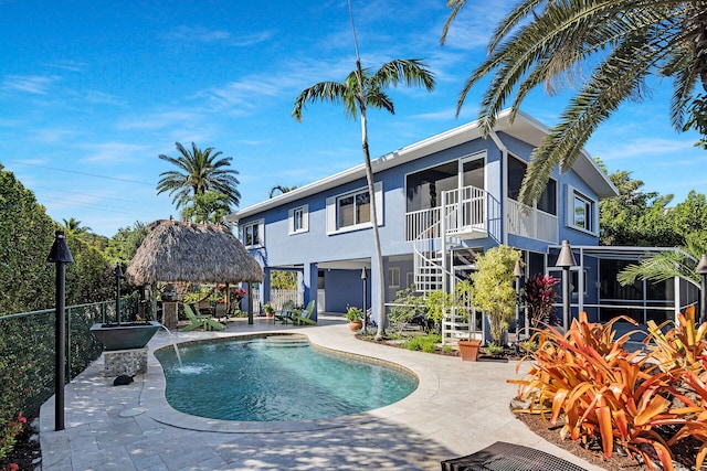 view of swimming pool featuring a gazebo, a patio area, a sunroom, and pool water feature