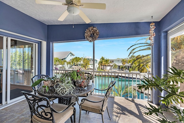 sunroom / solarium featuring a water view, ceiling fan, and a healthy amount of sunlight