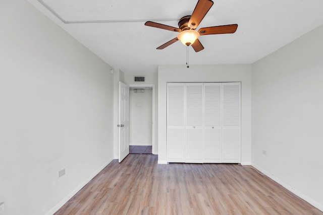 unfurnished bedroom with ceiling fan, light wood-type flooring, and a closet