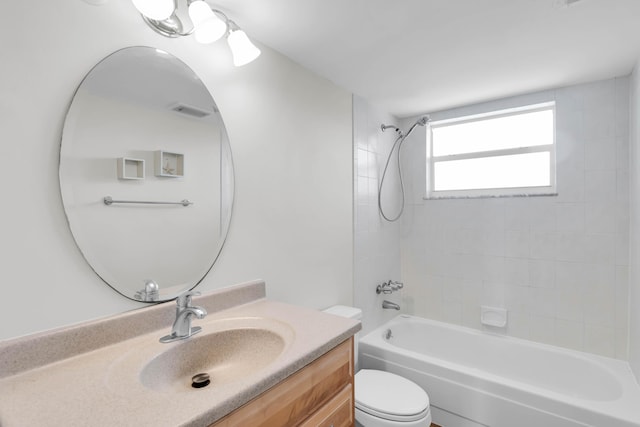 full bathroom featuring tiled shower / bath, vanity, and toilet