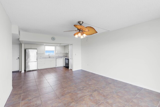 unfurnished living room with sink, a textured ceiling, ceiling fan, and dark tile patterned flooring