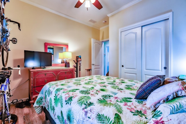 bedroom featuring crown molding, a closet, visible vents, ceiling fan, and wood finished floors