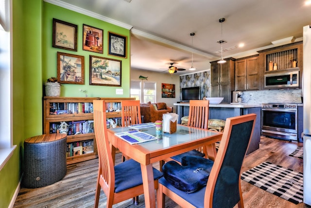 dining space featuring a ceiling fan, dark wood-type flooring, and crown molding