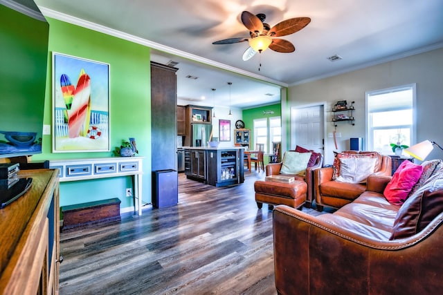 living area with a wealth of natural light, dark wood-style flooring, visible vents, and crown molding