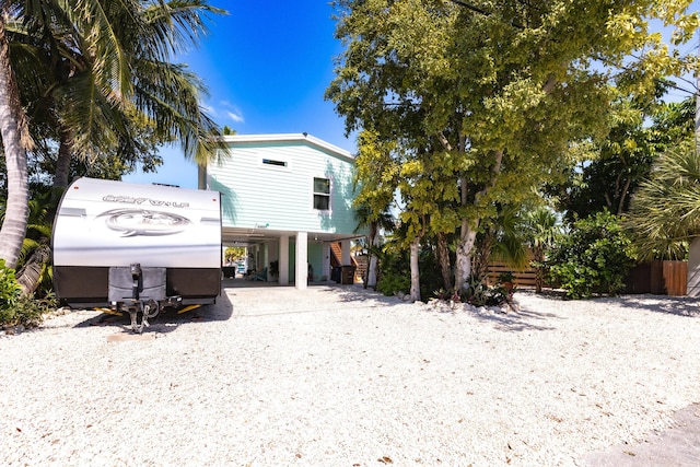 back of house featuring driveway, stairs, and a carport