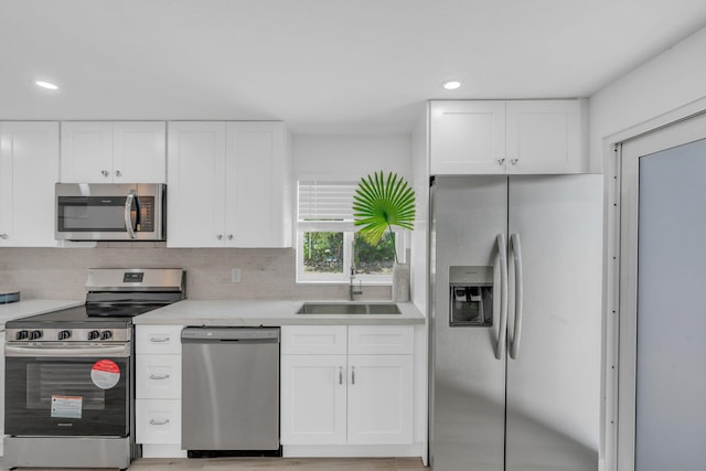 kitchen with stainless steel appliances, sink, and white cabinets