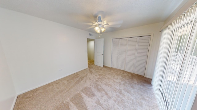 unfurnished bedroom with visible vents, light colored carpet, ceiling fan, a textured ceiling, and a closet