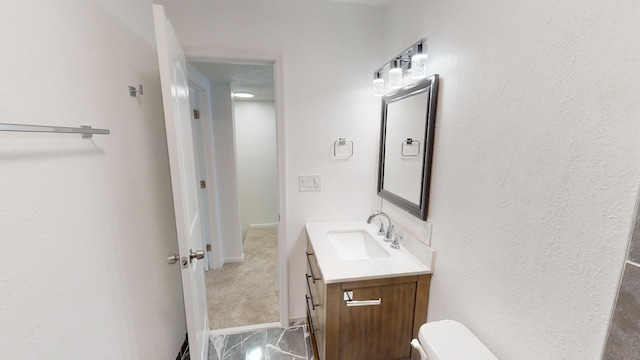 half bath with baseboards, vanity, and toilet