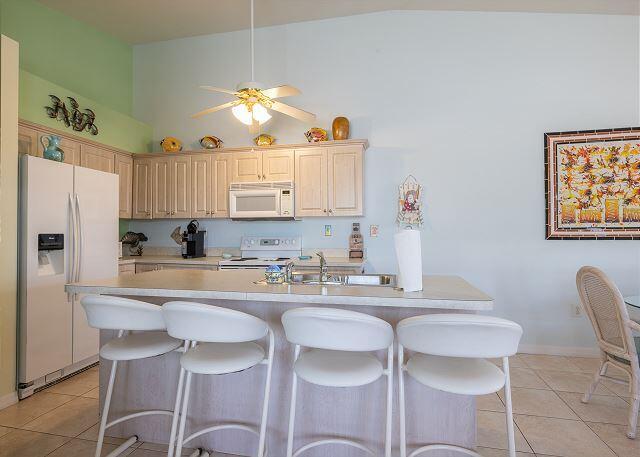 kitchen with an island with sink, sink, light tile patterned floors, ceiling fan, and white appliances