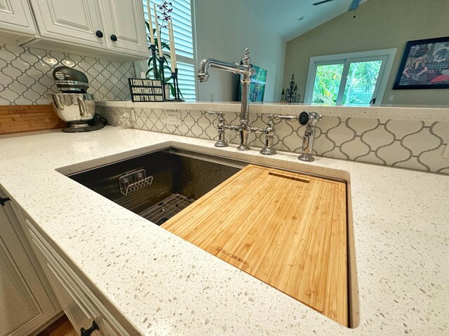 details featuring light stone counters, backsplash, and sink