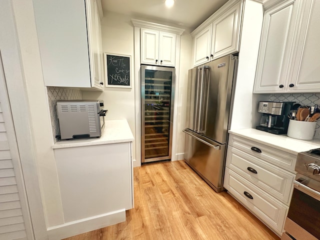 kitchen with white cabinetry, backsplash, beverage cooler, stainless steel appliances, and light wood-type flooring