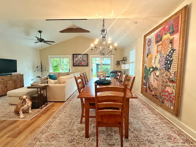 dining area featuring lofted ceiling, ceiling fan with notable chandelier, and light wood-type flooring