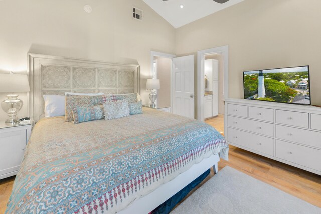 bedroom with ensuite bath, high vaulted ceiling, and light hardwood / wood-style flooring