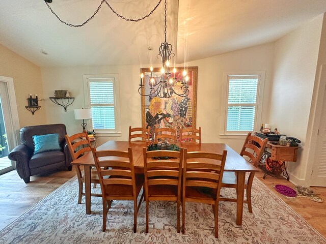 dining area with lofted ceiling, hardwood / wood-style flooring, and a chandelier