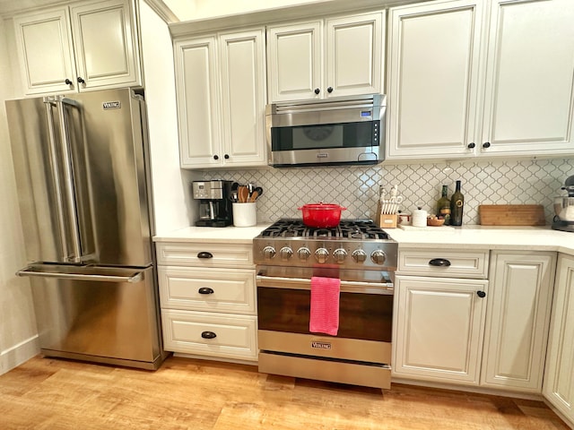 kitchen with appliances with stainless steel finishes, light wood-type flooring, and backsplash